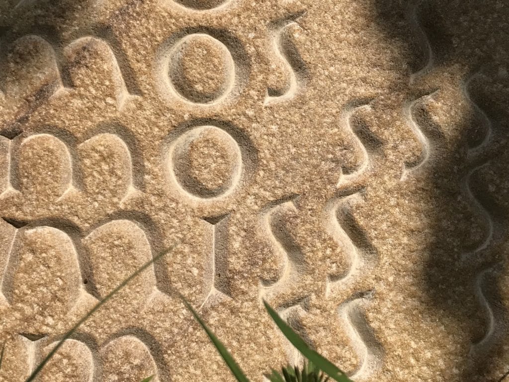 Sculpture showing the word moss disintegrating as it repeats over the stone surface