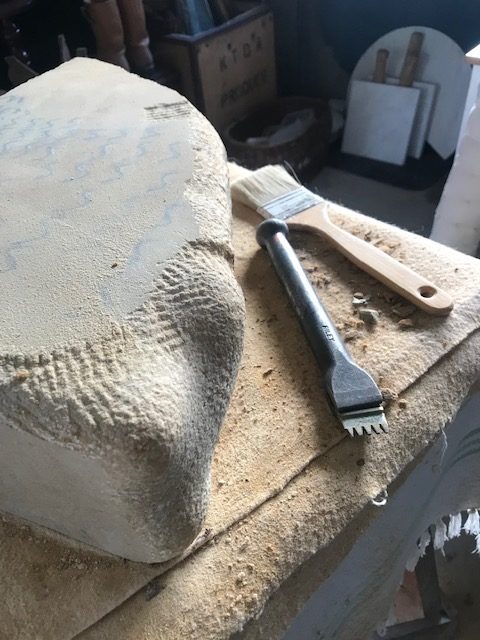 Partly carved stone, chisel and brush